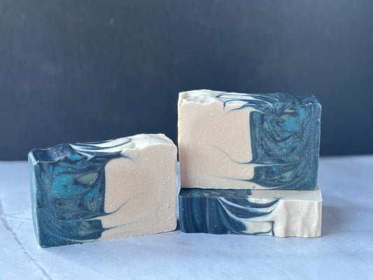 Three bars of soap with a marbled design on a white surface with a dark background