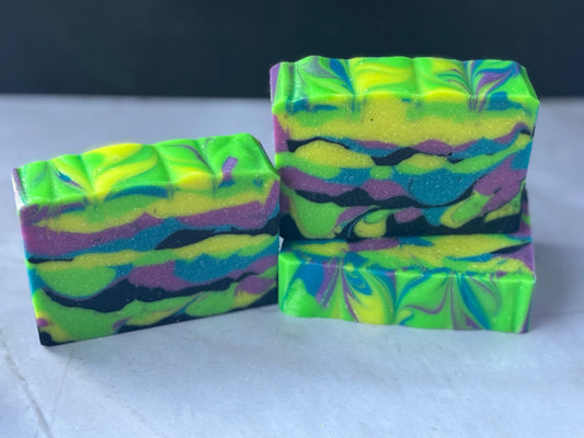 Three colorful soap bars with a neon tie-dye pattern on a white surface.