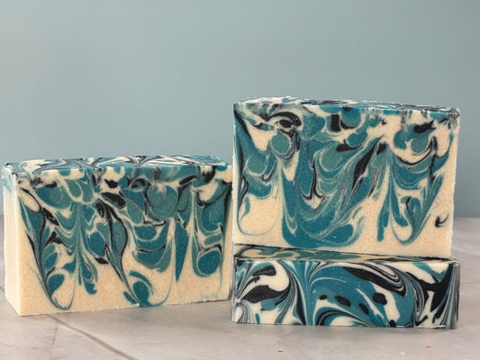 Three bars of marbled soap with blue and black patterns on a gray background