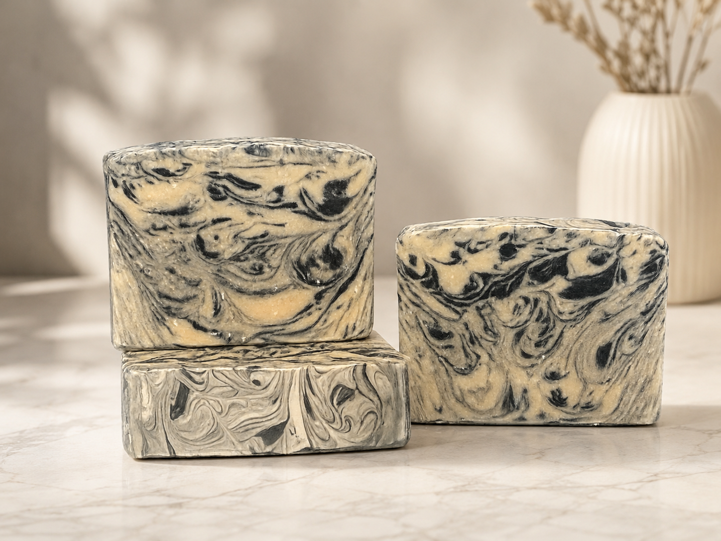 Three black and white marbled soaps on a marble countertop 