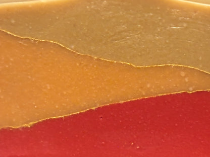 A close-up of a layered product with three horizontal color bands: a top tan-beige section, a middle golden-orange section, and a bottom red section.